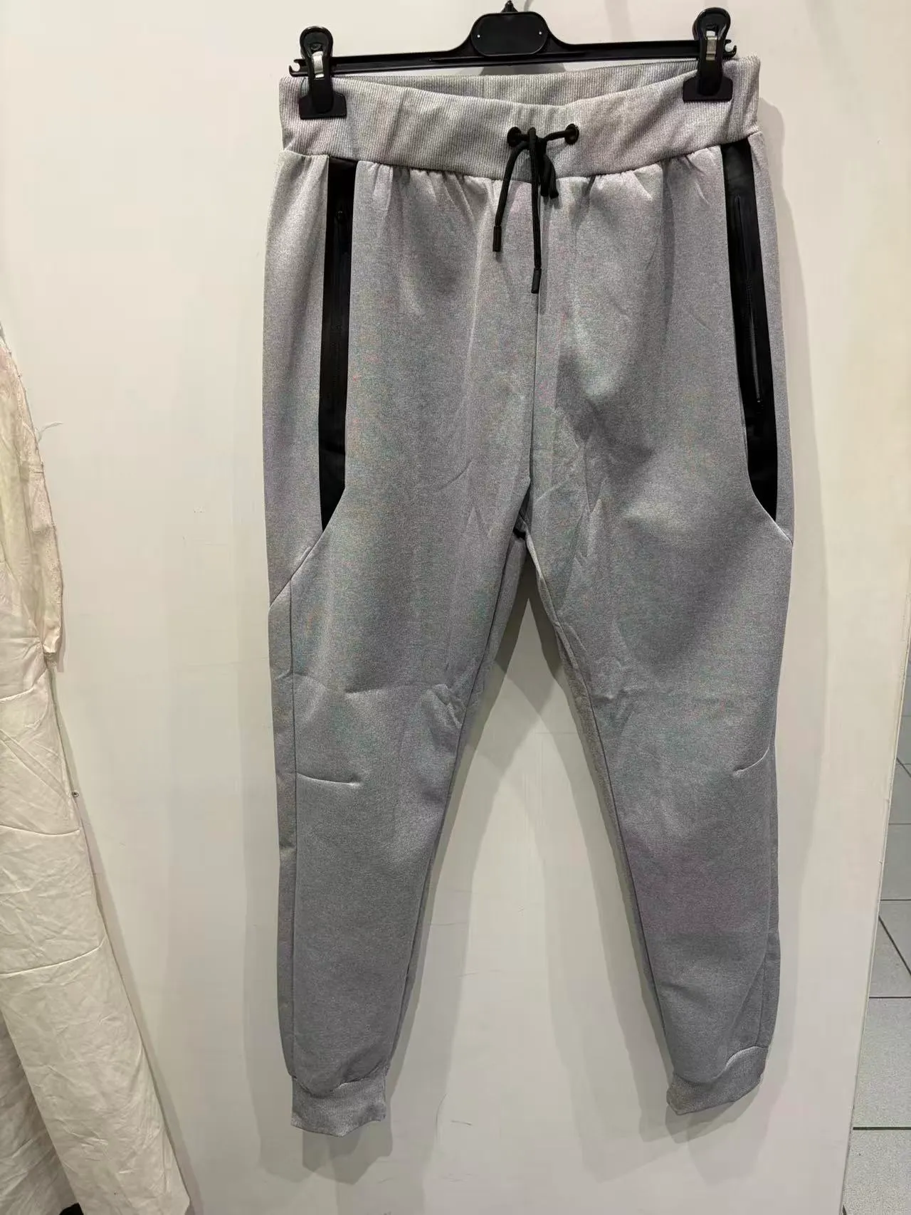 Pantaloni jogger grigi con coulisse, pannelli neri con zip e fondo elasticizzato, vista frontale