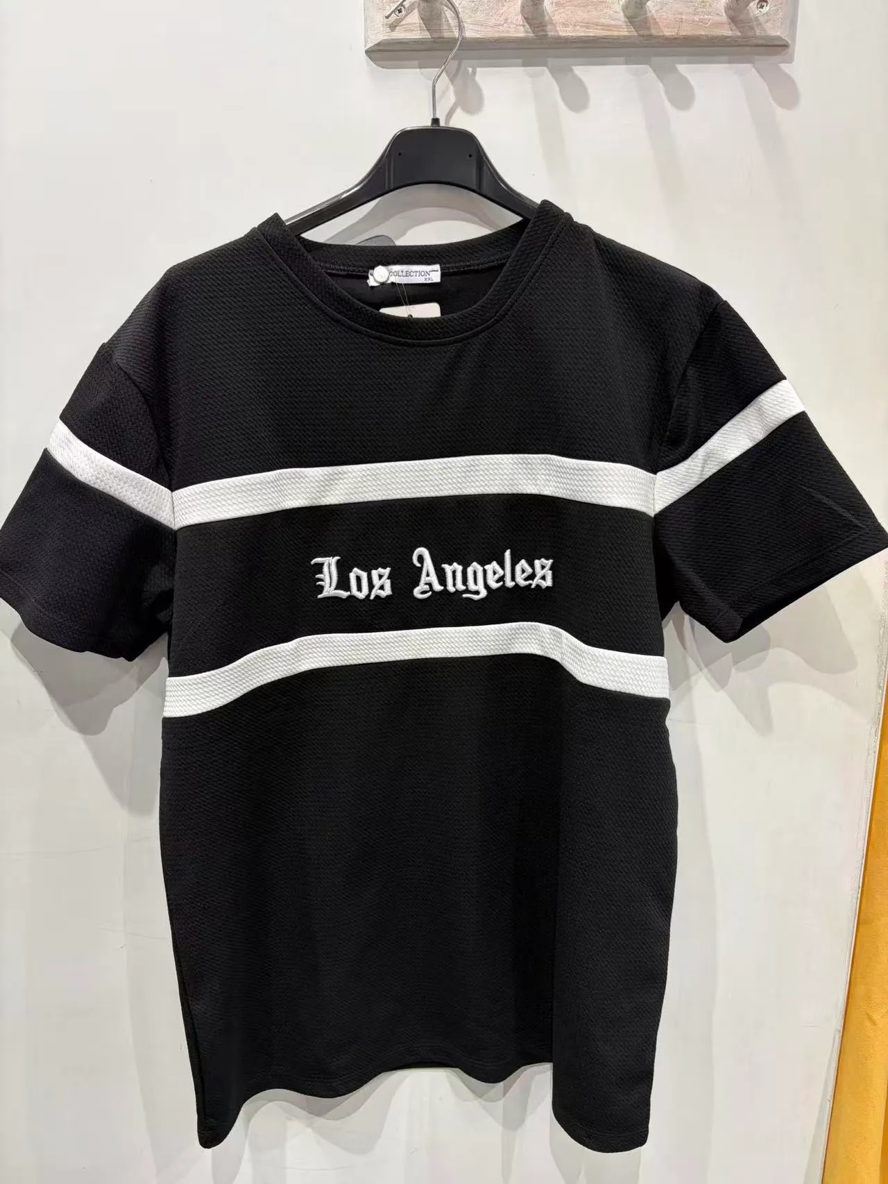 T-shirt nera con righe bianche e testo frontale, vista frontale