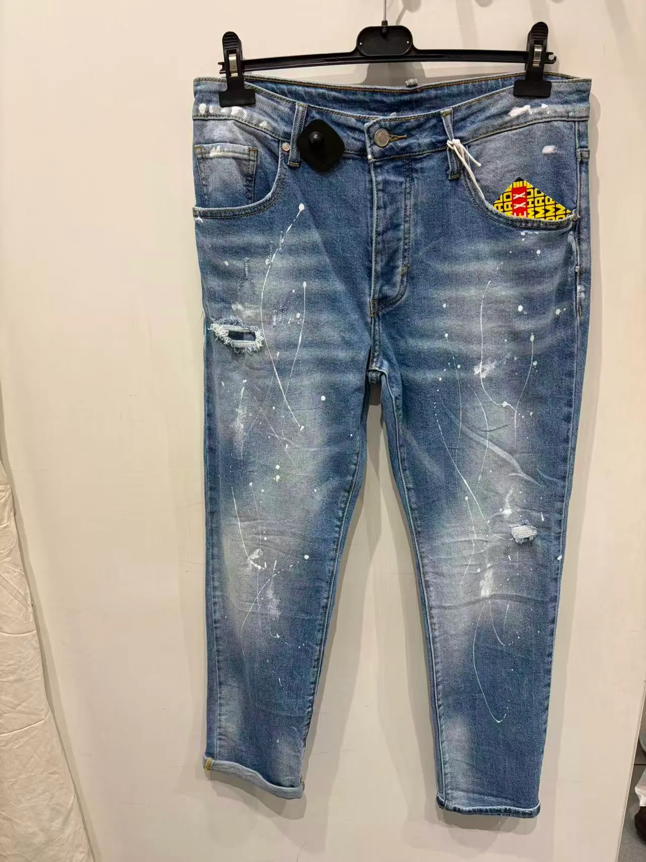 Pantaloni blu slim con effetto schizzi e toppa colorata, vista frontale