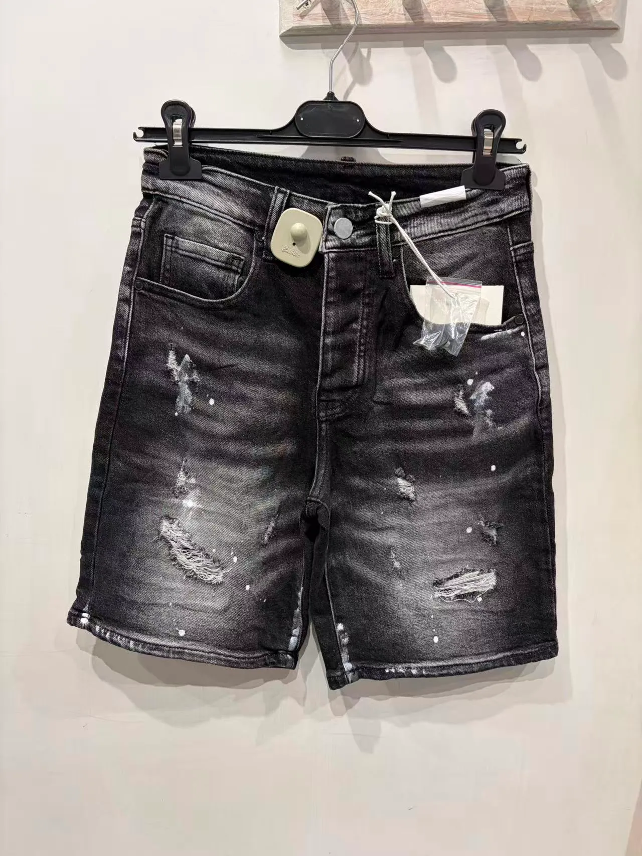 Pantaloncini neri slavati con borchie e strappi, vista frontale