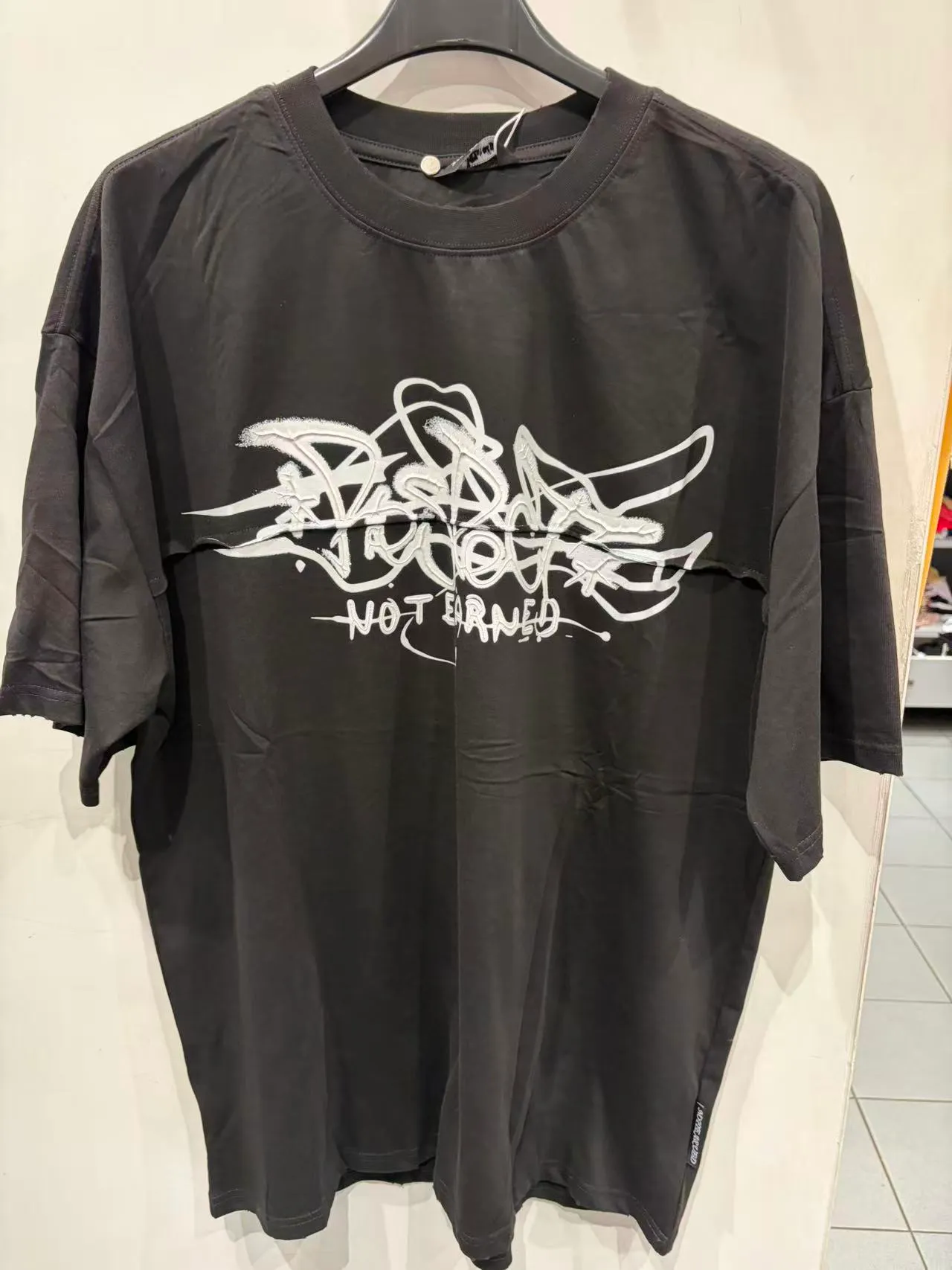 T-shirt oversize nera con stampa grafica bianca, vista frontale