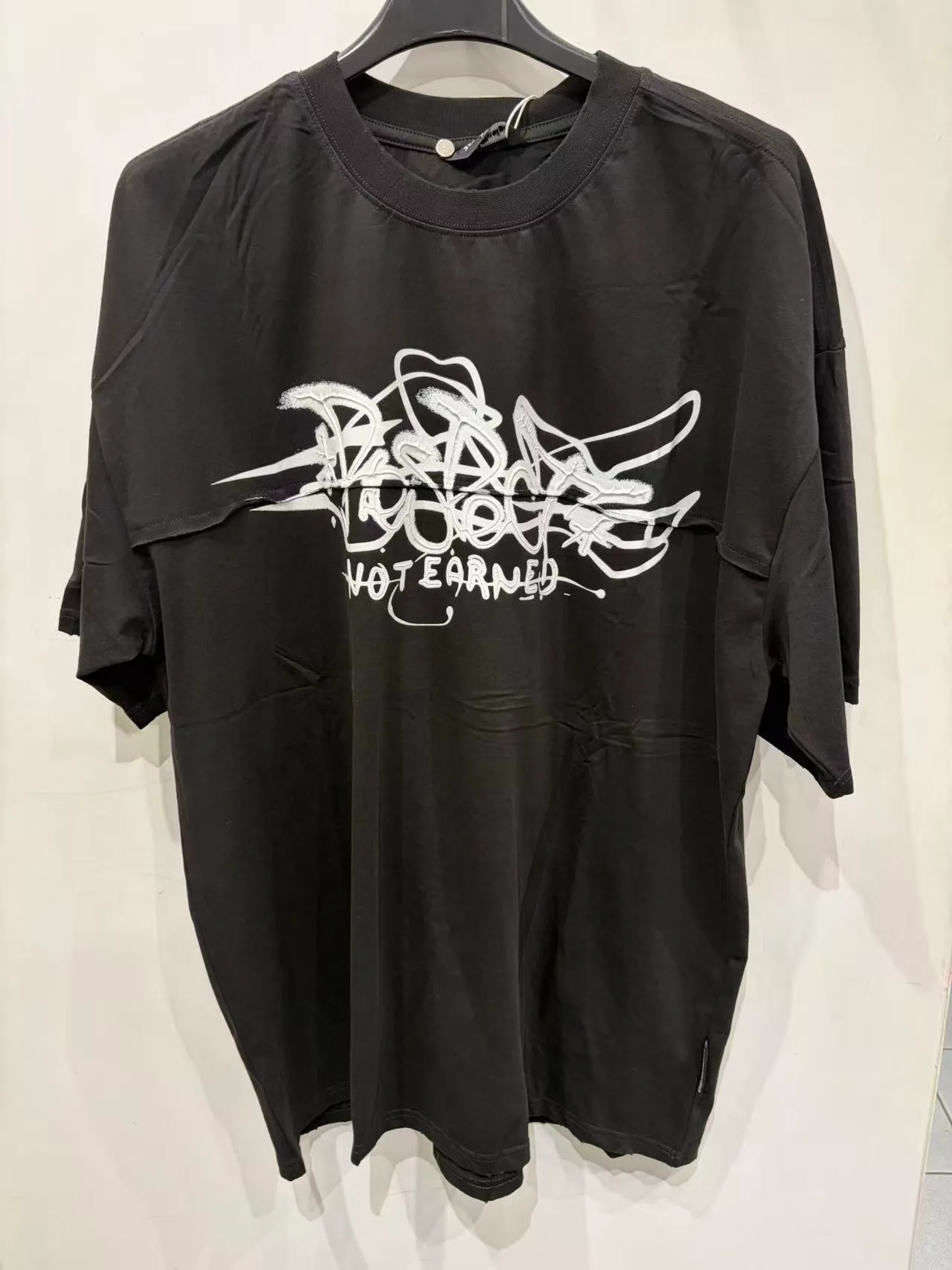 T-shirt nera con grande grafica tipografica bianca, vista frontale